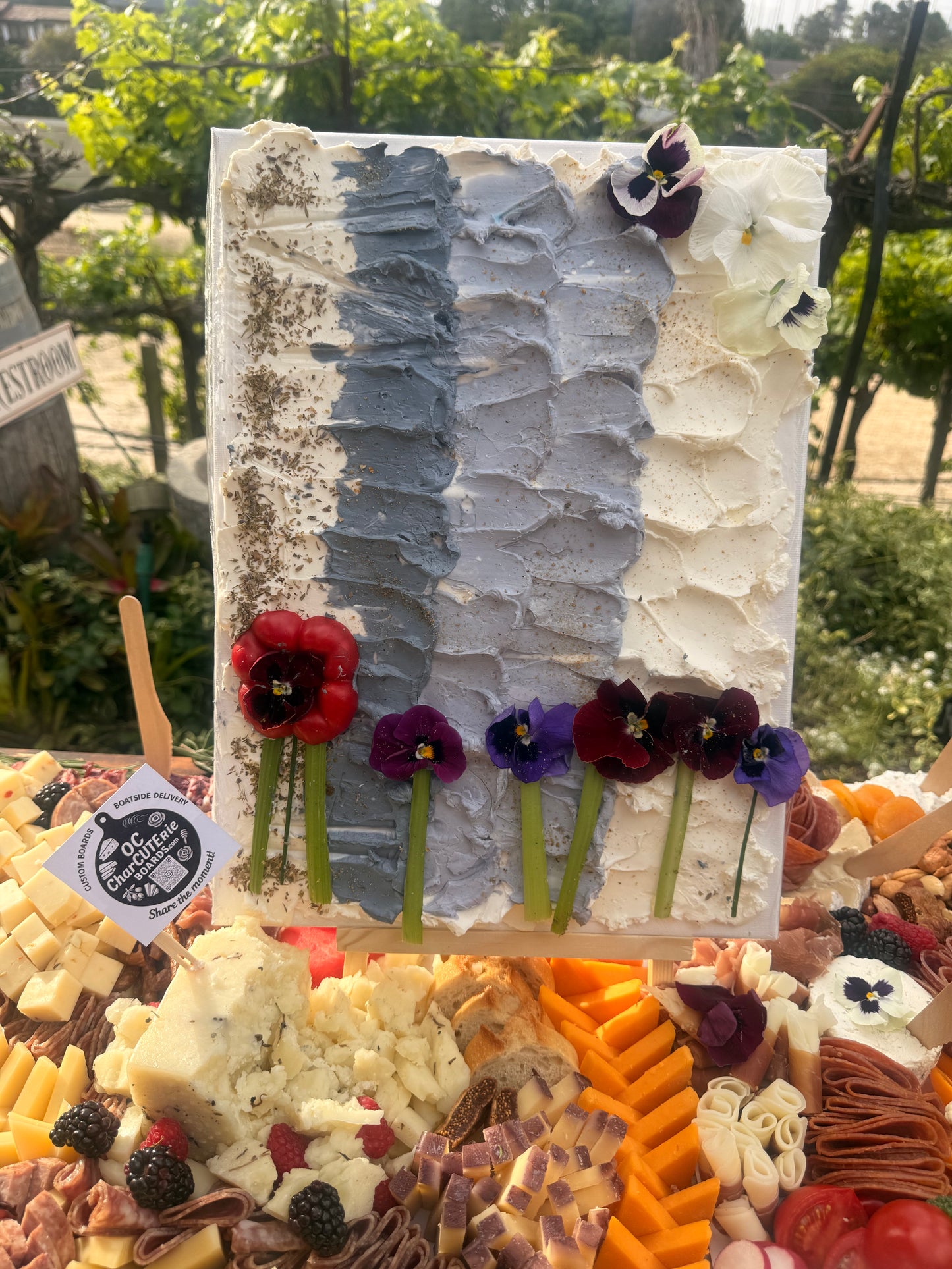 Edible floral cheese canvas painting on easel with crackers – OC Charcuterie Boards, Newport Beach