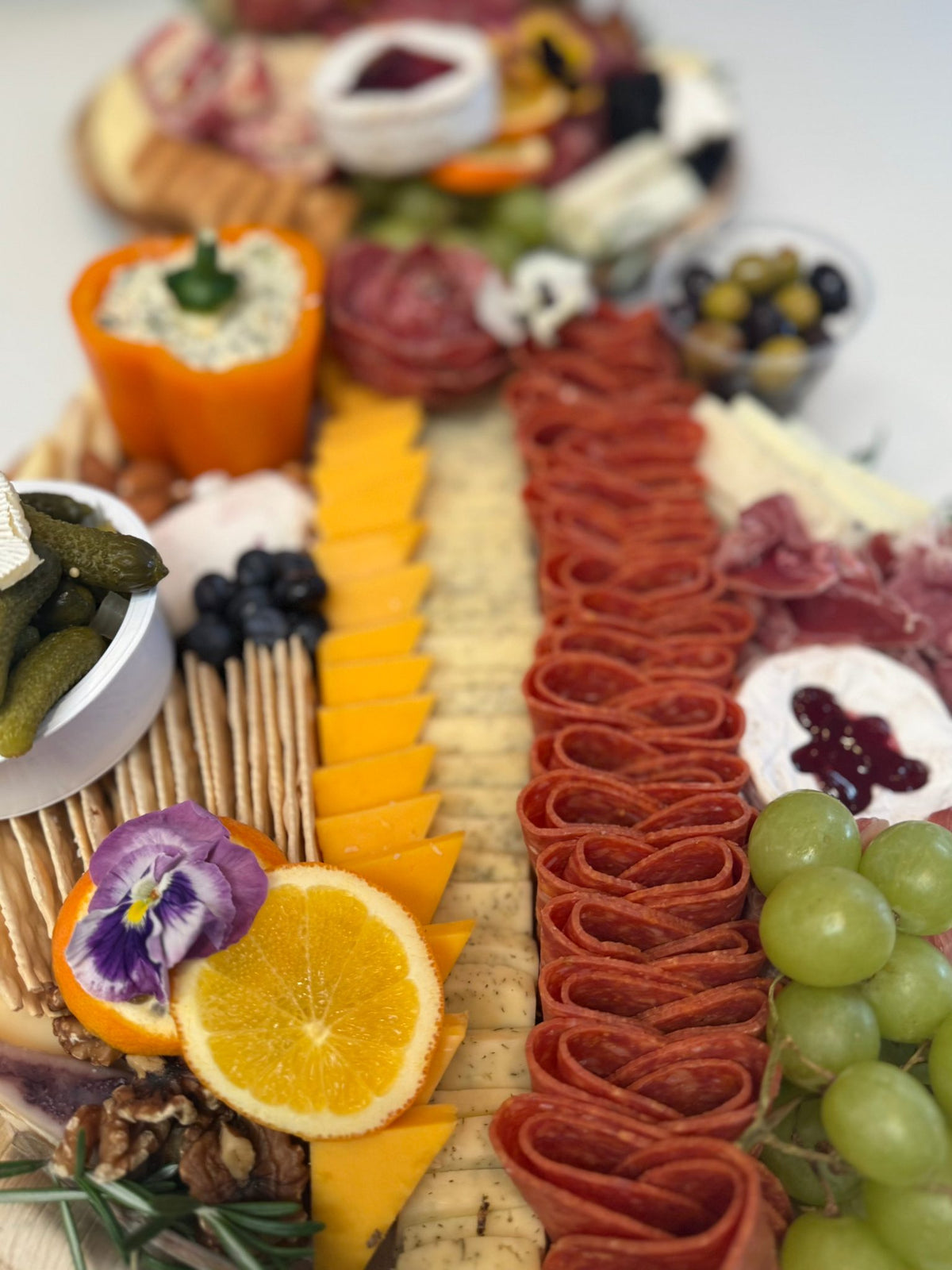 Close-up top-down view of medium charcuterie board on wooden board with sliced cheese for Orange County catering
